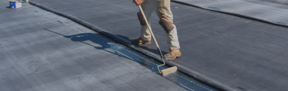 Man sealing a roof with a roller